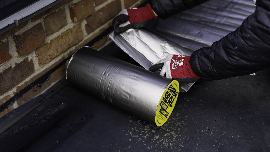 Supraseal weatherproofing tape being pressed into place below a gutter against brickwork